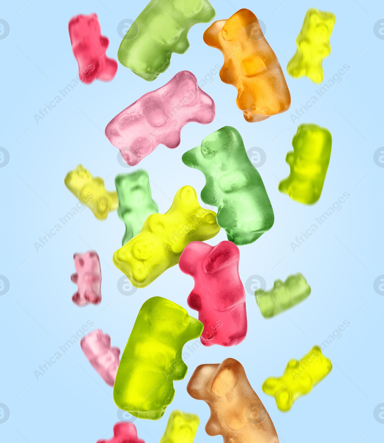 Image of Sweet jelly candies in shape of bear falling against light blue background