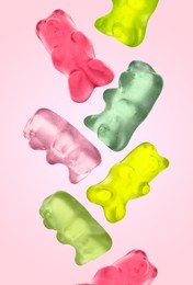 Image of Sweet jelly candies in shape of bear falling against pink background