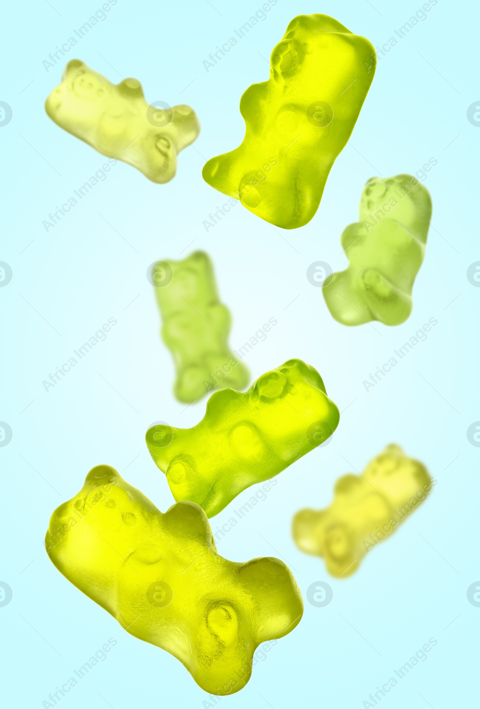 Image of Sweet jelly candies in shape of bear falling against light blue background