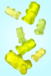 Image of Sweet jelly candies in shape of bear falling against light blue background
