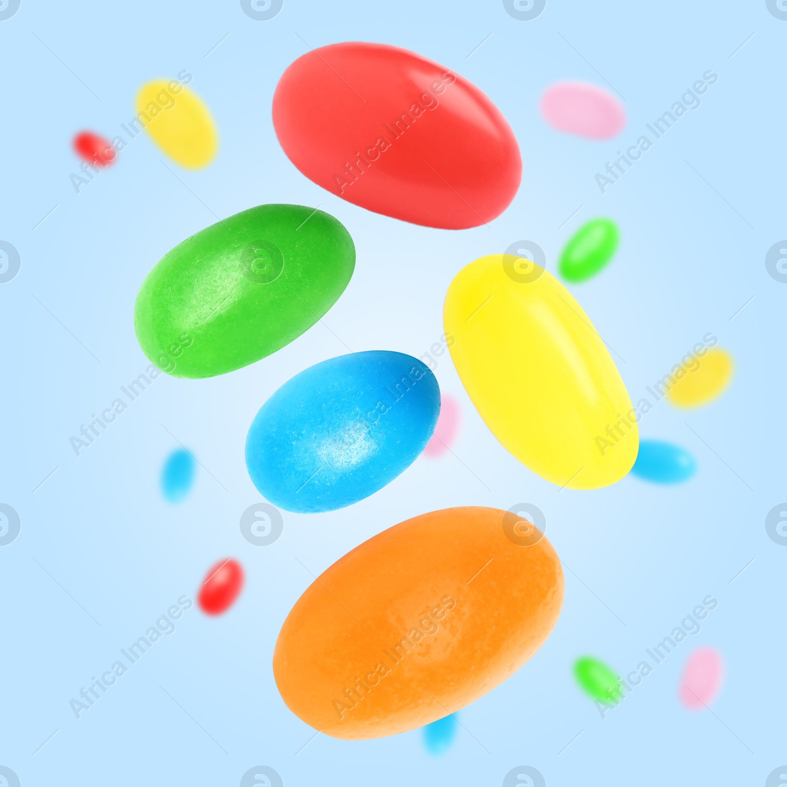 Image of Sweet jelly beans falling against light blue background