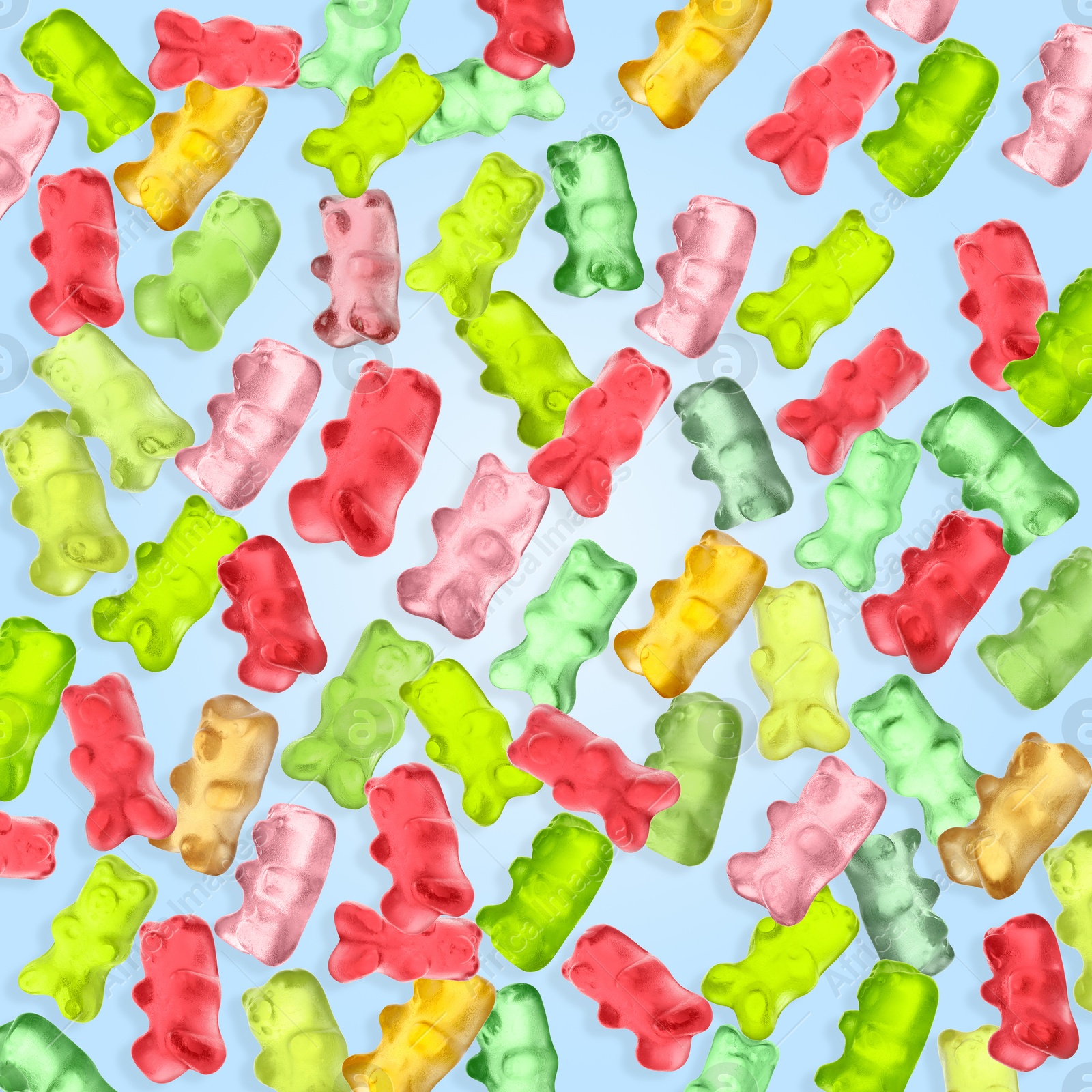 Image of Gummy bears in air on light blue background. Jelly candies