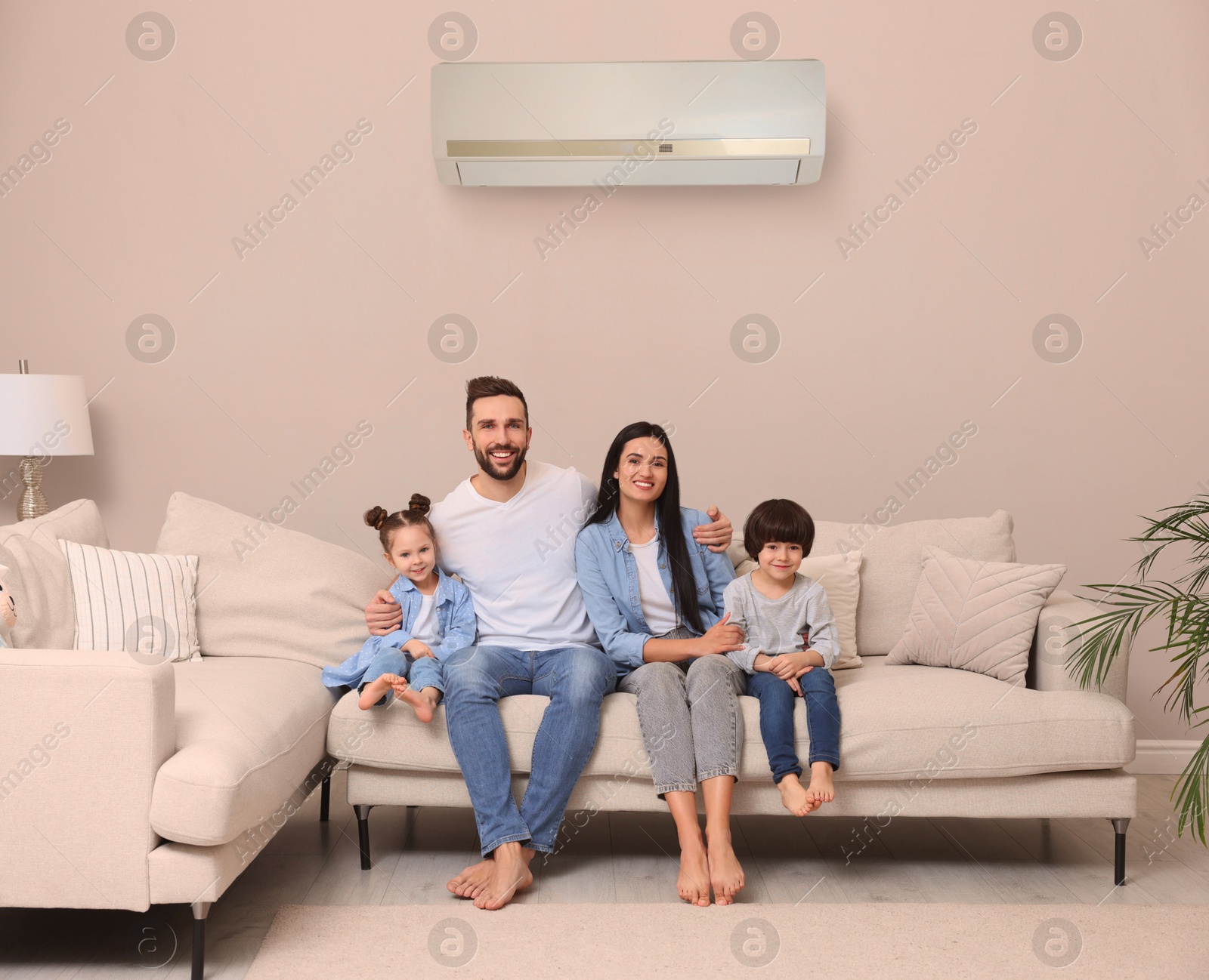 Happy family on sofa in living room. Air conditioner keeping comfortable temperature in room Image of Happy family on sofa in living room. Air conditioner keeping comfortable temperature in room