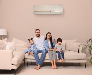 Image of Happy family on sofa in living room. Air conditioner keeping comfortable temperature in room
