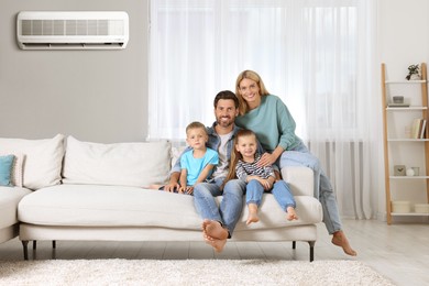 Image of Happy family with children on sofa at home. Air conditioner keeping comfortable temperature in room