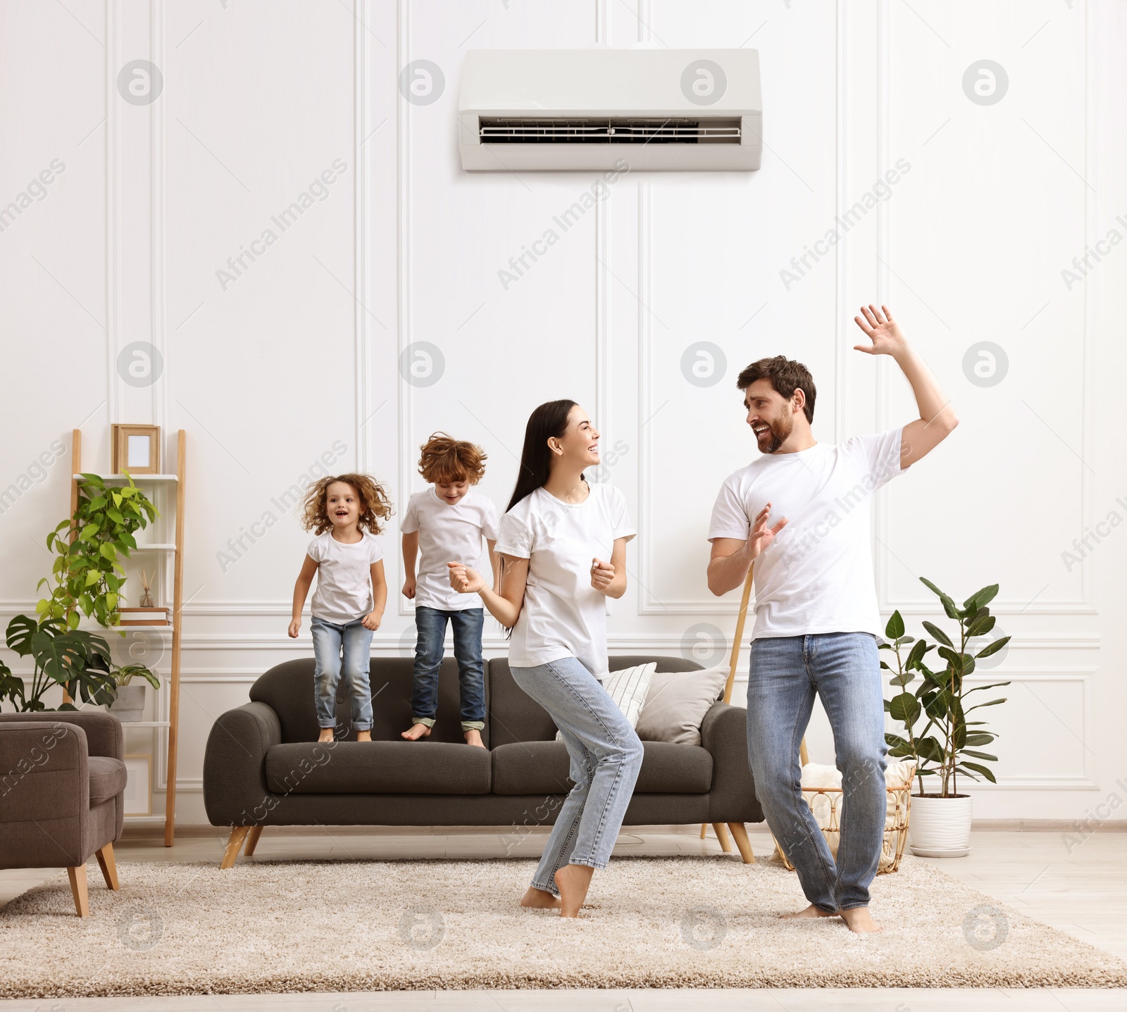 Image of Happy family having fun in living room. Air conditioner keeping comfortable temperature in room