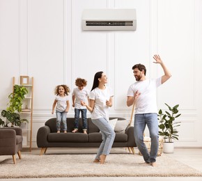 Image of Happy family having fun in living room. Air conditioner keeping comfortable temperature in room