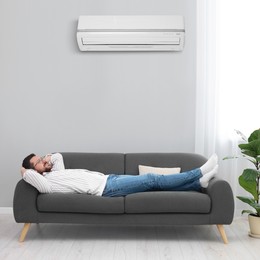 Image of Happy man relaxing on sofa at home. Air conditioner keeping comfortable temperature in room