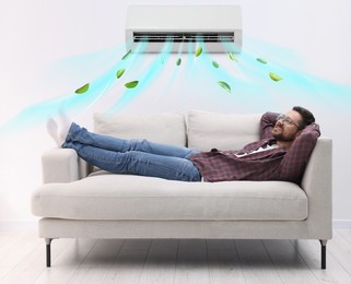 Image of Happy man relaxing on sofa at home. Air conditioner keeping comfortable temperature in room