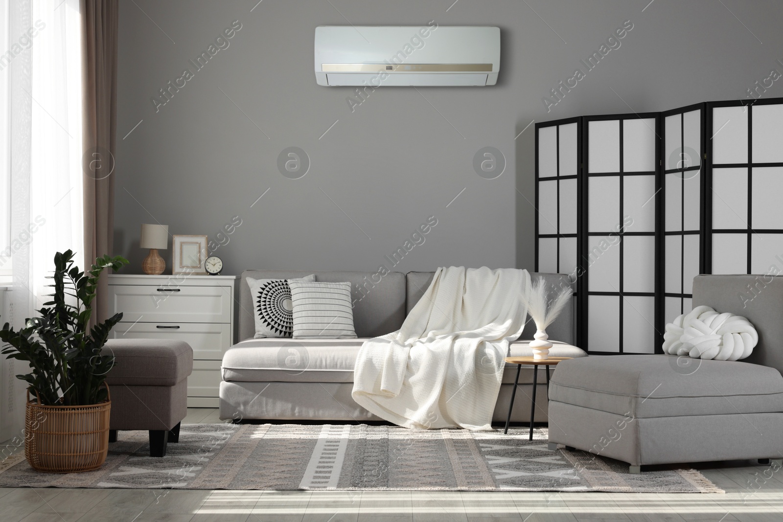 Sofa with blanket and folding screen in room. Air conditioner keeping comfortable temperature indoors Image of Sofa with blanket and folding screen in room. Air conditioner keeping comfortable temperature indoors