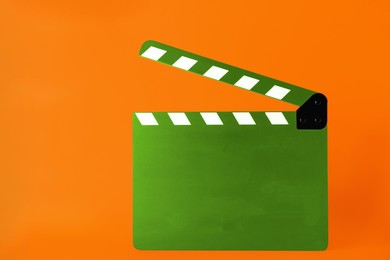 Image of Green clapper board on orange background, space for text. Film industry