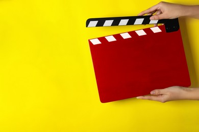 Image of Woman holding red clapperboard on yellow background, closeup with space for text. Film industry