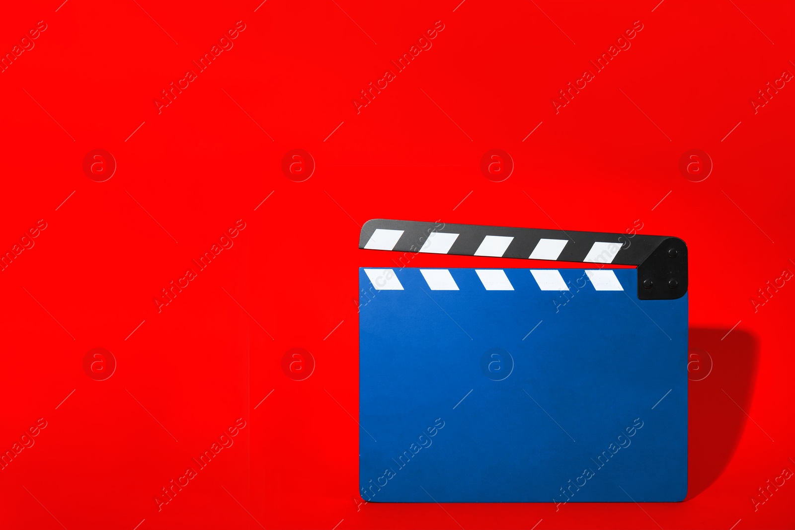 Image of Blue clapperboard on red background, space for text. Film industry