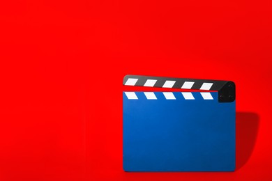 Image of Blue clapperboard on red background, space for text. Film industry