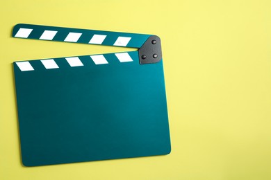 Image of Teal clapperboard on yellow background, top view with space for text. Film industry