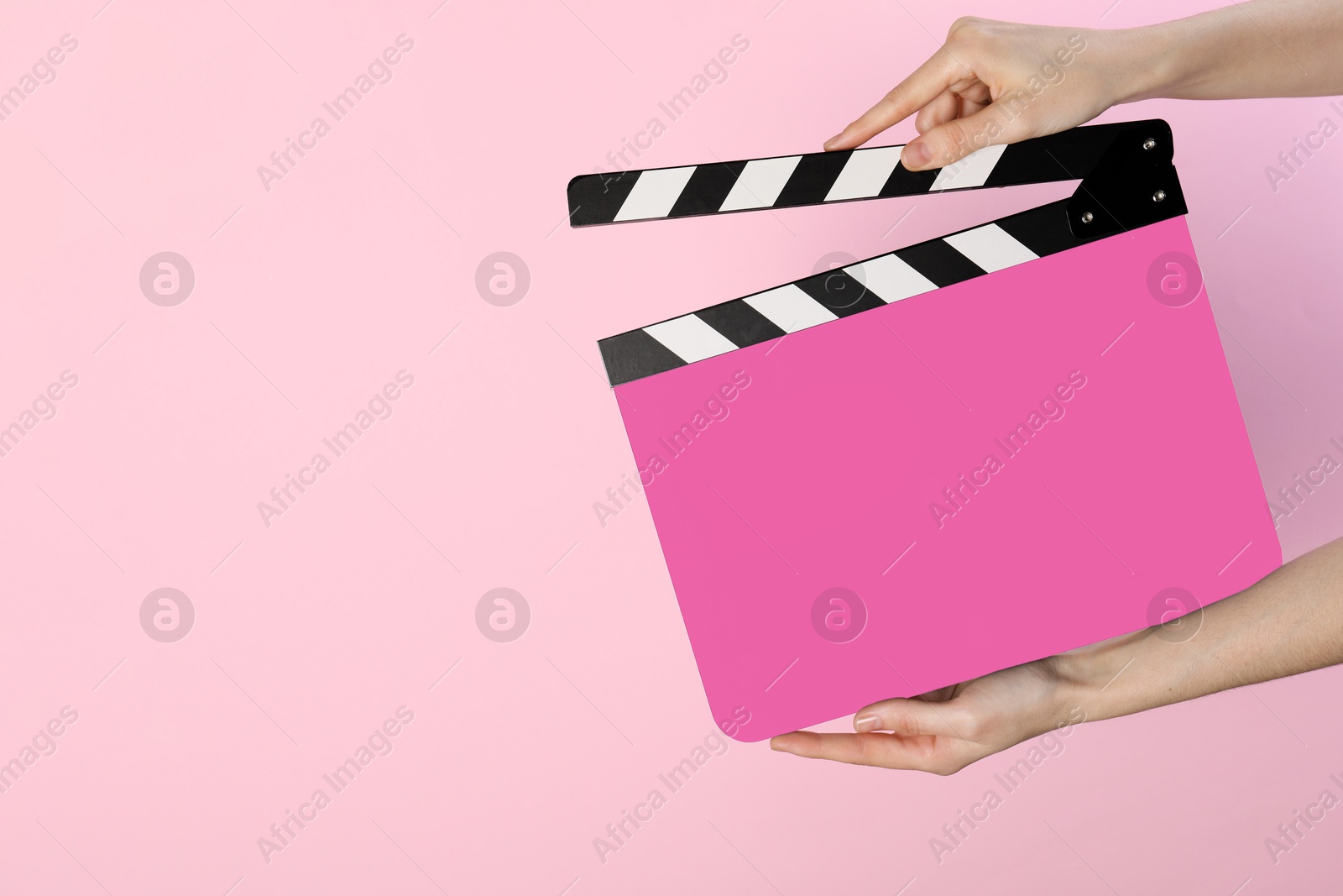 Image of Woman holding color clapperboard on pink background, closeup with space for text. Film industry