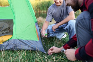 Photo of Father and son setting up camping tent outdoors, closeup