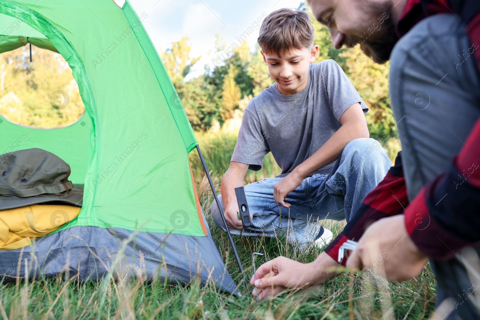 Photo of Father and son setting up camping tent outdoors, closeup