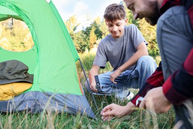Photo of Father and son setting up camping tent outdoors, closeup