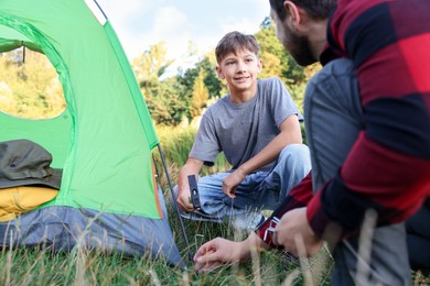 Photo of Father and son setting up camping tent outdoors, closeup