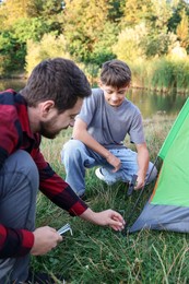 Photo of Father and son setting up camping tent outdoors