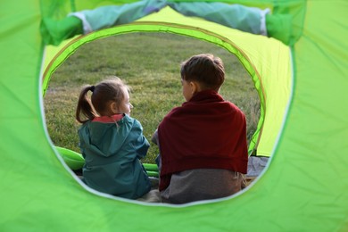 Photo of Brother and sister in camping tent, view from outside