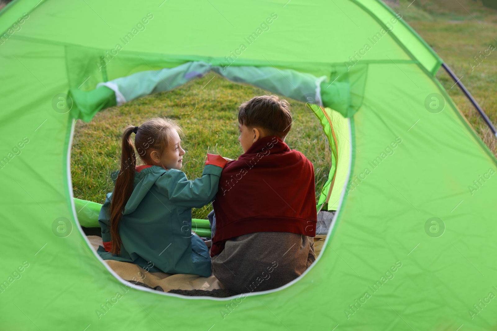 Photo of Brother and sister in camping tent, view from outside