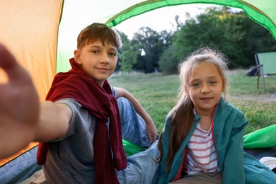 Photo of Brother and sister taking selfie in camping tent outdoors