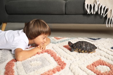 Photo of Little boy and his cute turtle on floor at home. Domestic pet