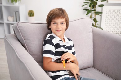 Photo of Dreams come true. Little boy with pet rat on armchair at home