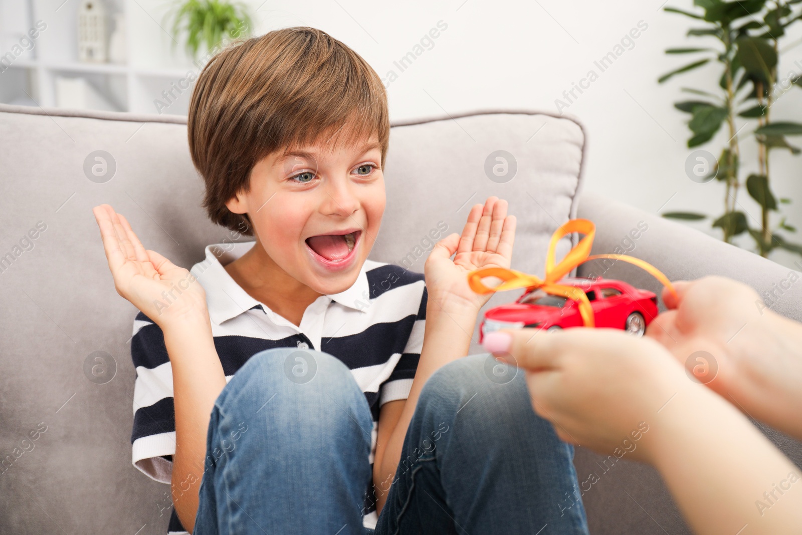 Dreams come true. Mother presenting toy car to her happy son at home, closeup Photo of Dreams come true. Mother presenting toy car to her happy son at home, closeup