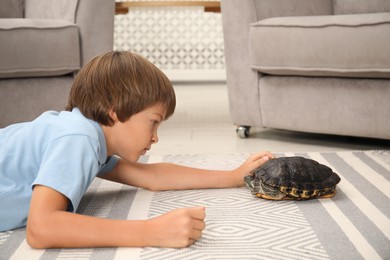 Photo of Little boy and his cute turtle on floor at home. Domestic pet