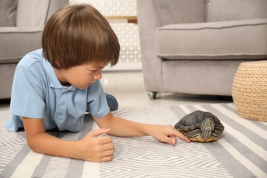 Photo of Little boy and cute turtle on floor at home. Domestic pet