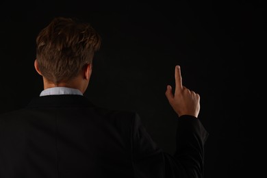 Photo of Man touching something on black background, back view