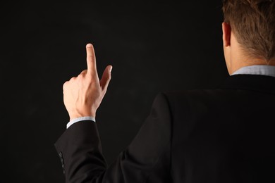 Photo of Man touching something on black background, back view