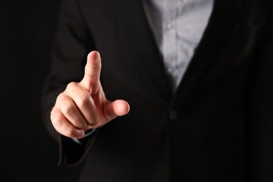 Photo of Man touching something on black background, closeup