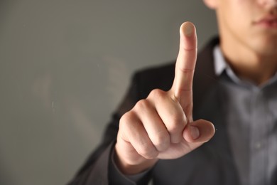 Photo of Man touching something on grey background, closeup. Space for text
