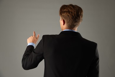 Photo of Man touching something on grey background, back view
