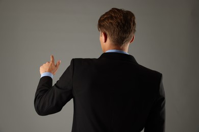 Photo of Man touching something on grey background, back view