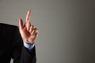 Photo of Man touching something on grey background, closeup. Space for text