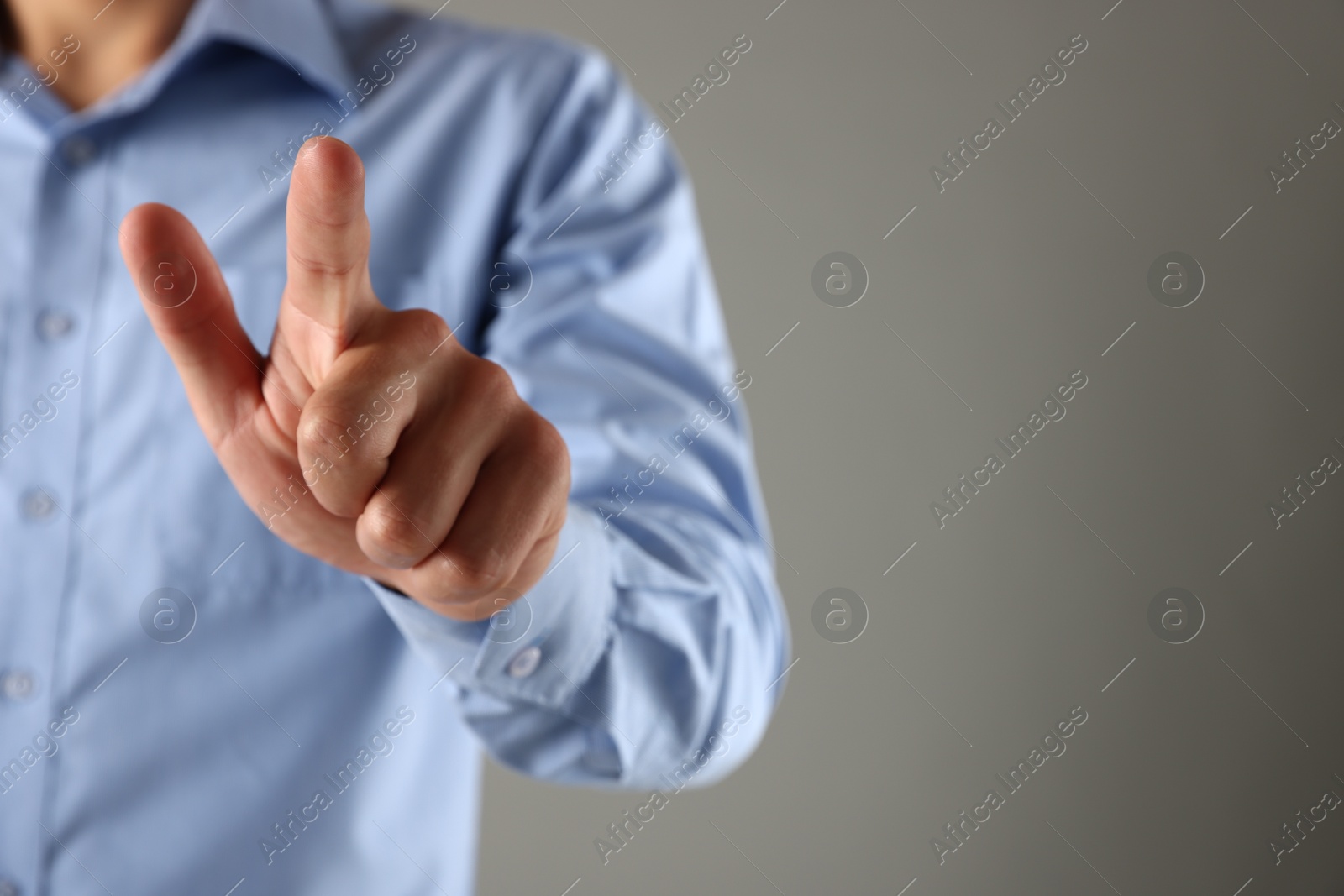 Photo of Man touching something on grey background, closeup. Space for text
