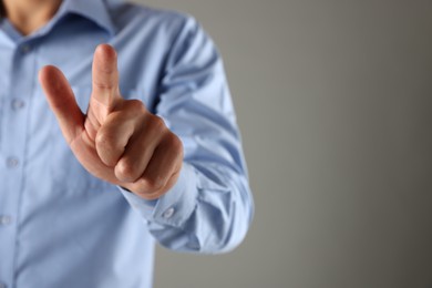 Photo of Man touching something on grey background, closeup. Space for text