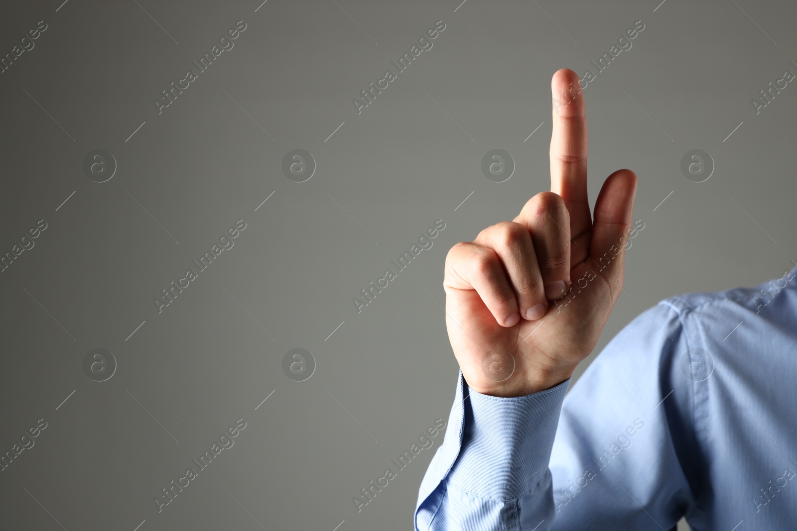 Photo of Man touching something on grey background, closeup. Space for text