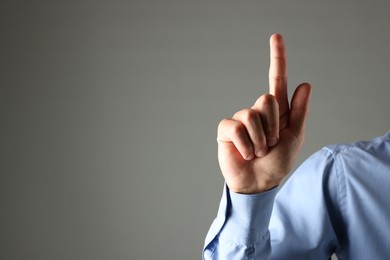 Photo of Man touching something on grey background, closeup. Space for text