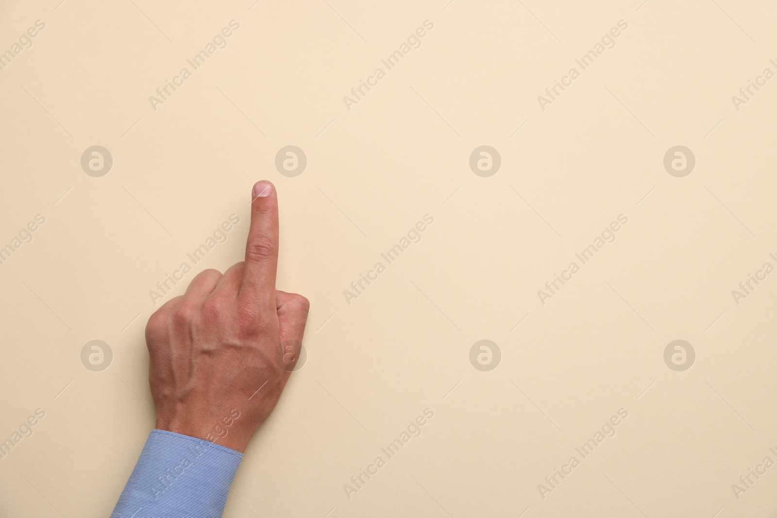 Man touching something on beige background, top view. Space for text Photo of Man touching something on beige background, top view. Space for text