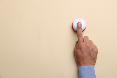 Photo of Man pressing button on beige background, top view. Space for text
