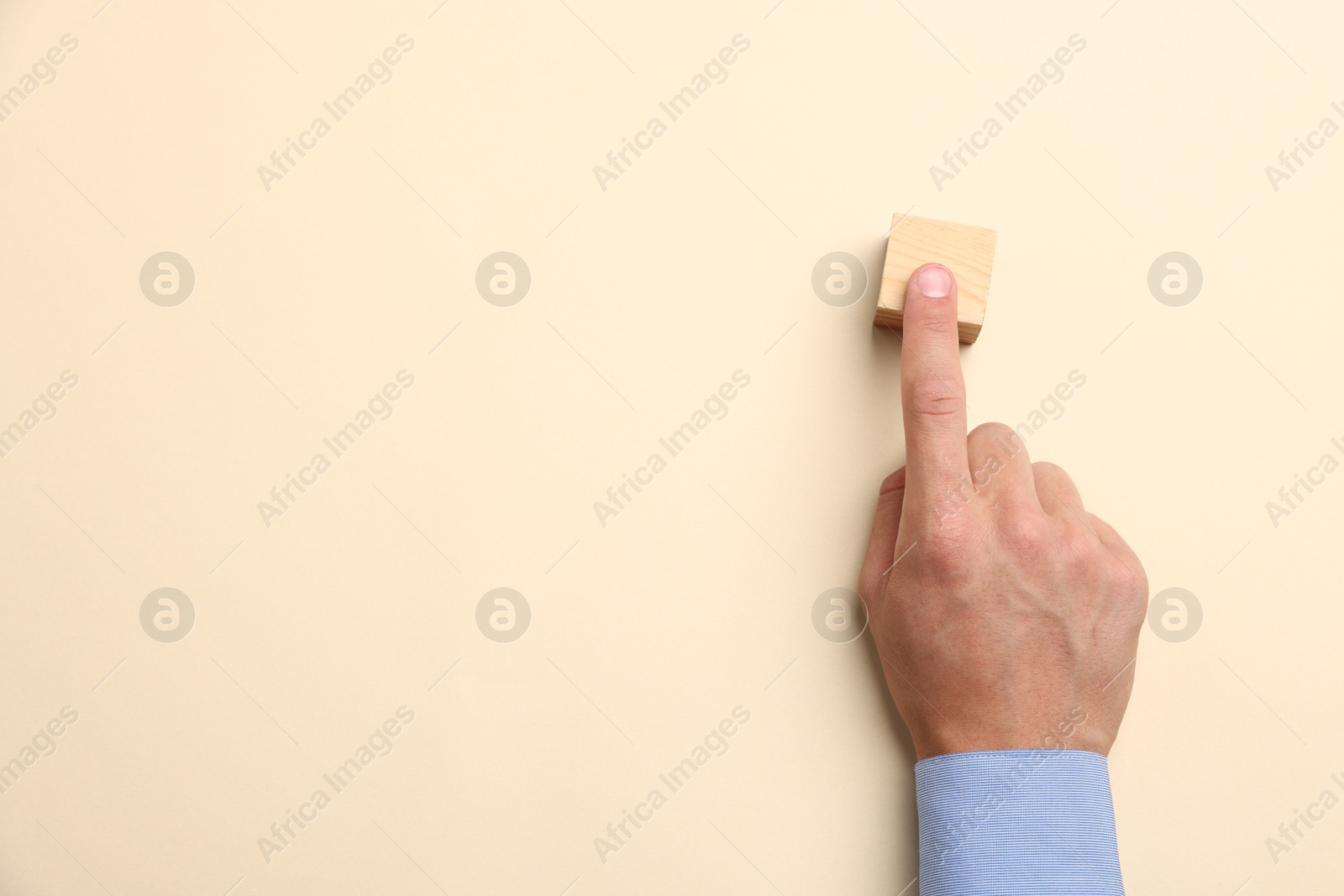 Man touching wooden cube on beige background, top view. Space for text Photo of Man touching wooden cube on beige background, top view. Space for text