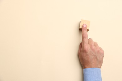 Photo of Man touching wooden cube on beige background, top view. Space for text