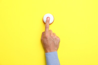 Photo of Man pressing button on yellow background, top view
