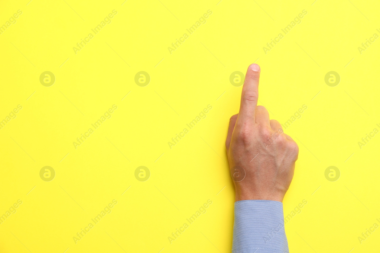 Man touching something on yellow background, top view. Space for text Photo of Man touching something on yellow background, top view. Space for text